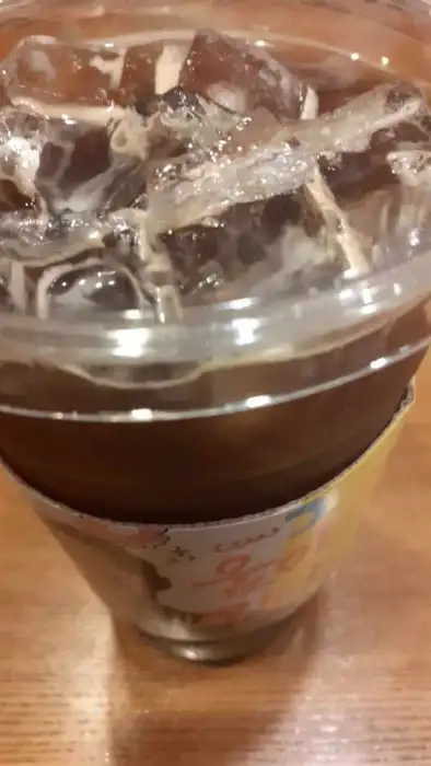 얼음이 가득한 아이스 아메리카노 컵의 상단 부분. 컵 홀더가 보인다.