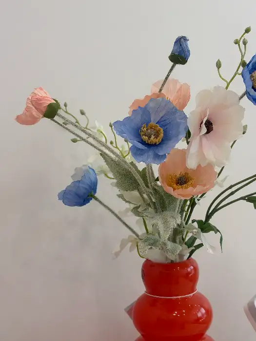 주황색 도자기에 담긴 분홍색, 파란색, 흰색의 다양한 꽃들