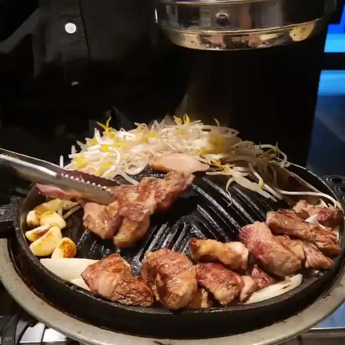 다양한 부위의 양고기와 숙주나물이 철판 위에서 익어가는 모습