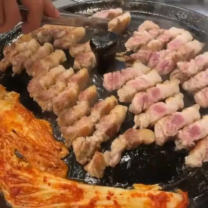 솥뚜껑 위에서 익어가는 삼겹살과 김치