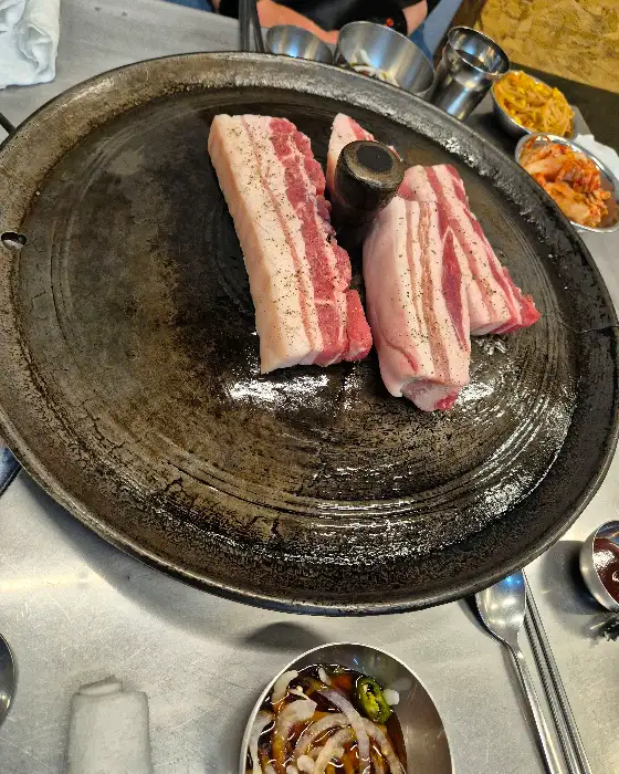 솥뚜껑 위에 놓인 두툼한 삼겹살 덩어리