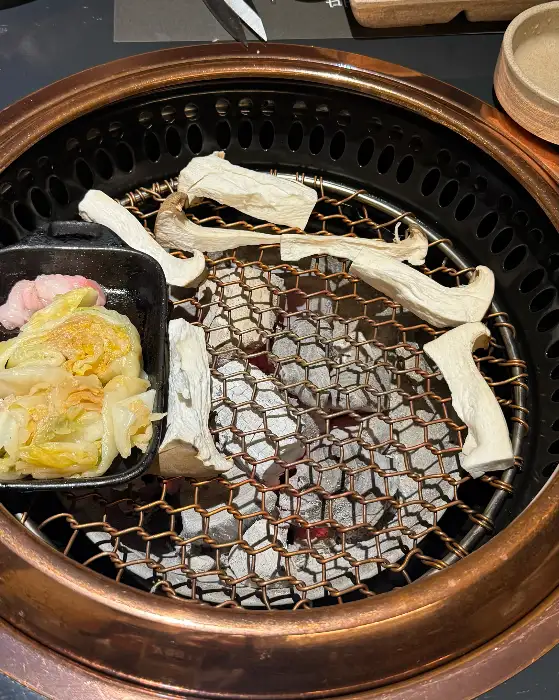 숯불 위에서 맛있게 구워지고 있는 한우와 버섯