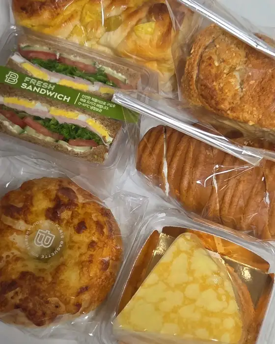 여러 종류의 빵과 샌드위치가 담긴 플라스틱 용기들