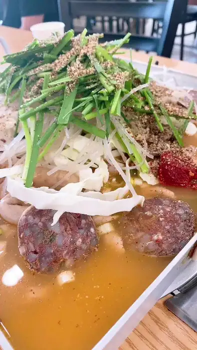 모듬 철판 볶음. 철판 위에 푸짐한 순대와 내장, 채소가 매콤한 양념과 함께 볶아져 있습니다.