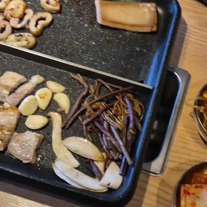 불판 위에 가지런히 구워지고 있는 막창과 곁들임 재료들