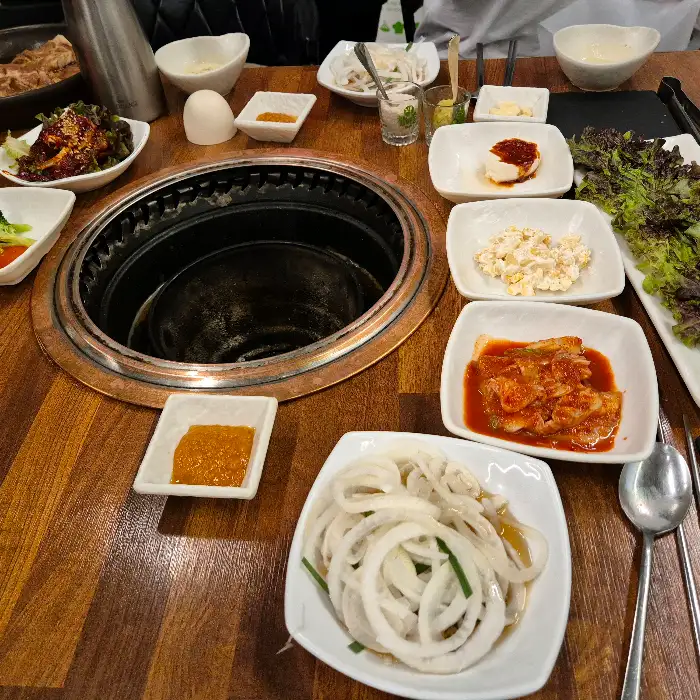 테이블에 차려진 다양한 밑반찬과 숯불구이용 원형 불판