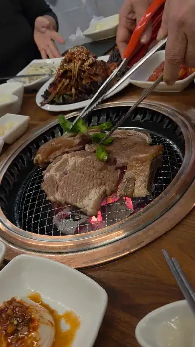 숯불 위에서 익어가는 돼지갈비와 곁들임 채소