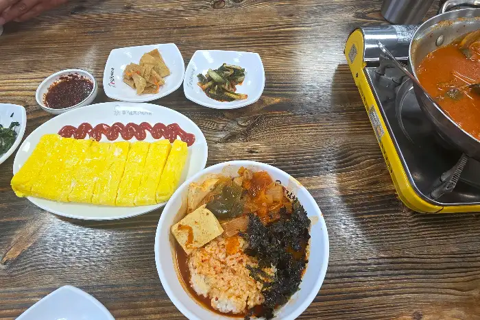 테이블에 놓인 김치찌개, 계란말이, 밥, 밑반찬들