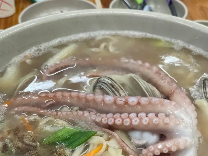 큼직한 낙지와 조개가 들어있는 칼국수. 국물이 뽀얗고 면발이 쫄깃해 보인다.