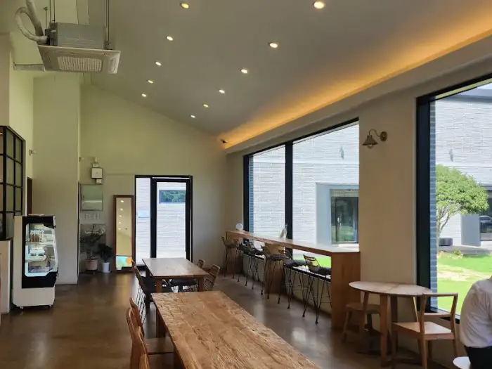 넓은 통창과 나무 테이블, 바 테이블이 있는 카페 내부