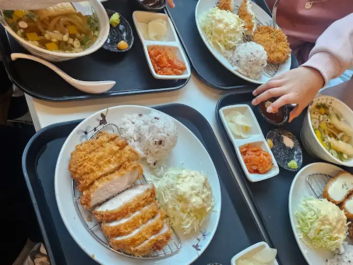 여러 명이 식사하고 있는 모습. 테이블마다 다양한 음식이 놓여 있습니다.