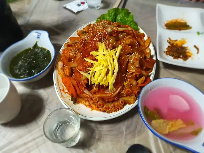 푸짐하게 차려진 낙지 덮밥과 곁들임 반찬
