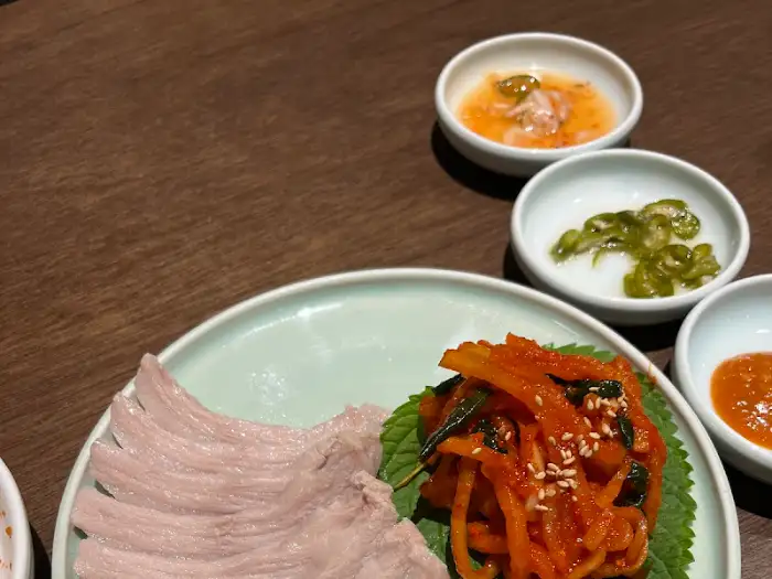 수육과 백김치가 함께 담긴 접시. 부드러운 수육의 결이 살아있습니다.