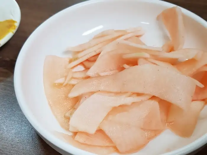 하얀 접시에 담긴 얇게 썬 무 절임