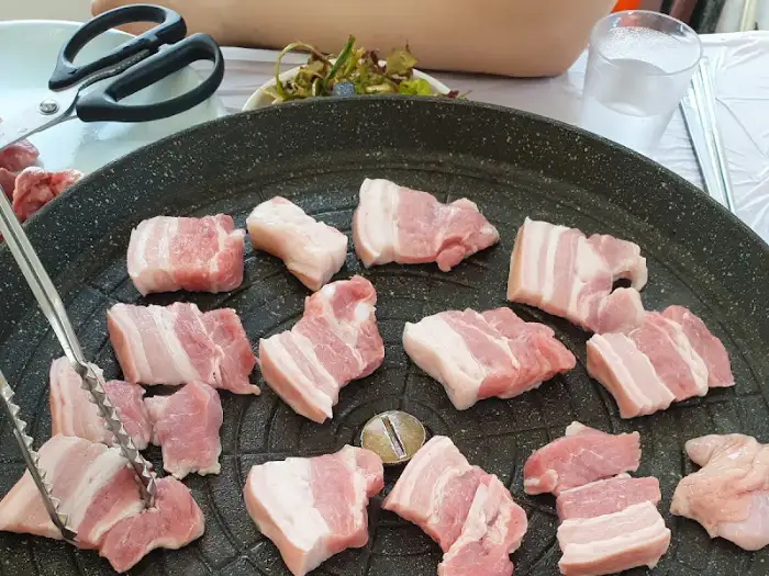 팬 위에 두툼한 삼겹살 덩어리가 놓여 있는 모습