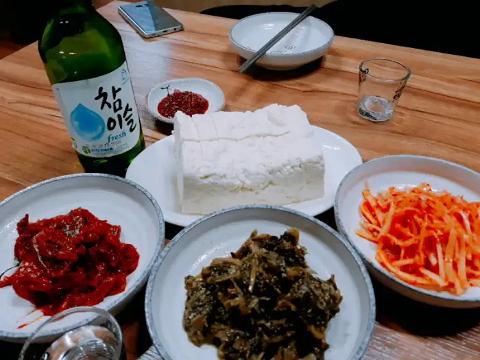 두부와 함께 놓인 소주병과 반찬들