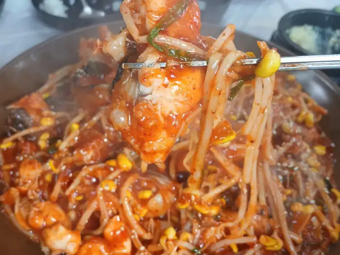 집게로 아구찜 속 흰살 생선과 콩나물을 집는 모습