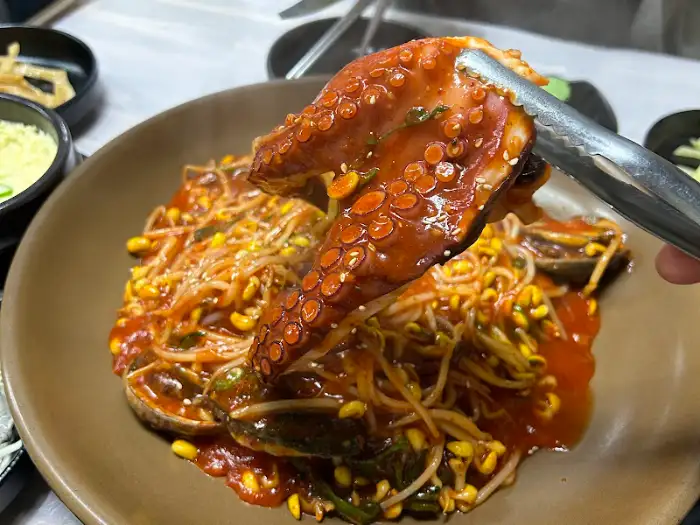 집게로 아구찜 속 문어 다리를 집어 올리는 모습