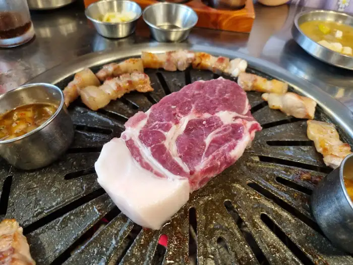 불판 위에서 맛있게 익어가는 흑돼지 삼겹살 부위