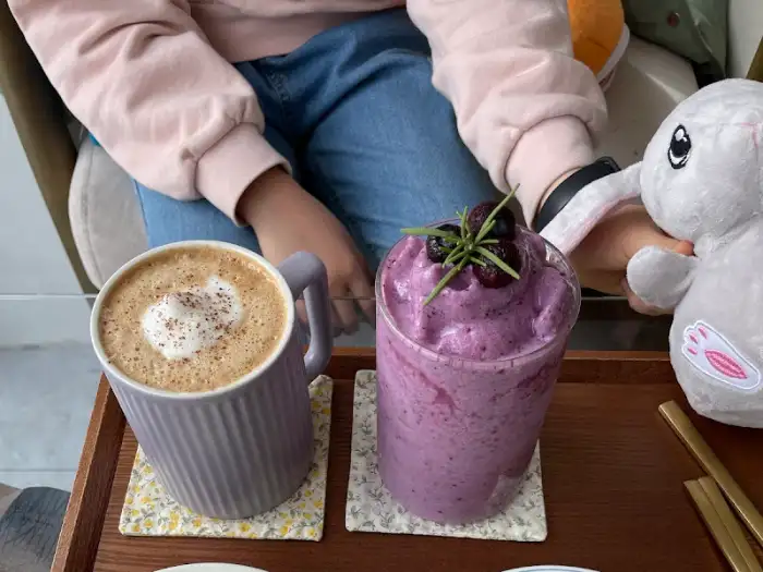 블루베리 스무디와 커피, 샌드위치가 테이블 위에 놓여 있다.