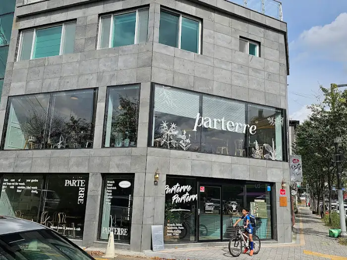 모던한 디자인의 회색 건물 외관, 커다란 유리창과 'parterre' 로고가 보임