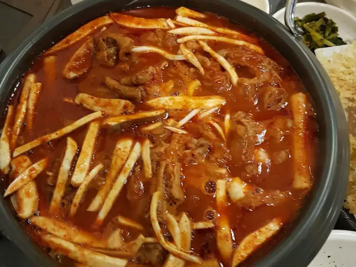국물닭발 냄비의 클로즈업 사진. 붉은 국물과 닭발, 떡 등이 푸짐하게 들어있습니다.