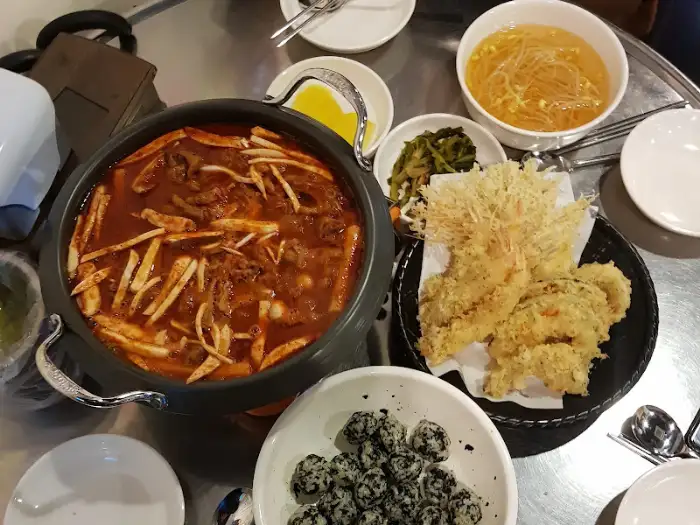 신홍불닭발본점의 다양한 음식들이 테이블에 차려진 모습. 닭발, 튀김, 주먹밥 등이 함께 보입니다.