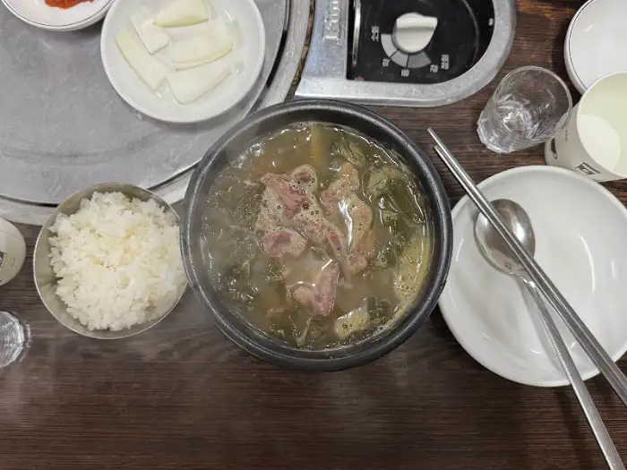 뚝배기에 담긴 해장국과 밥, 그리고 반찬들이 놓인 식탁 모습.
