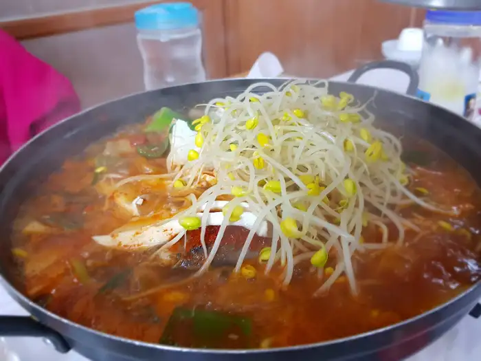 동태탕 냄비에 콩나물이 수북이 쌓여 있고, 국물이 끓고 있습니다.