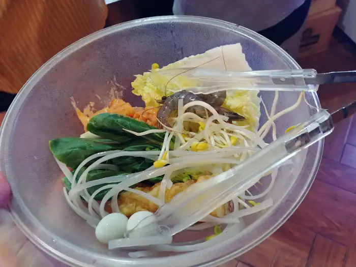 집게로 채소와 새우를 담고 있는 모습