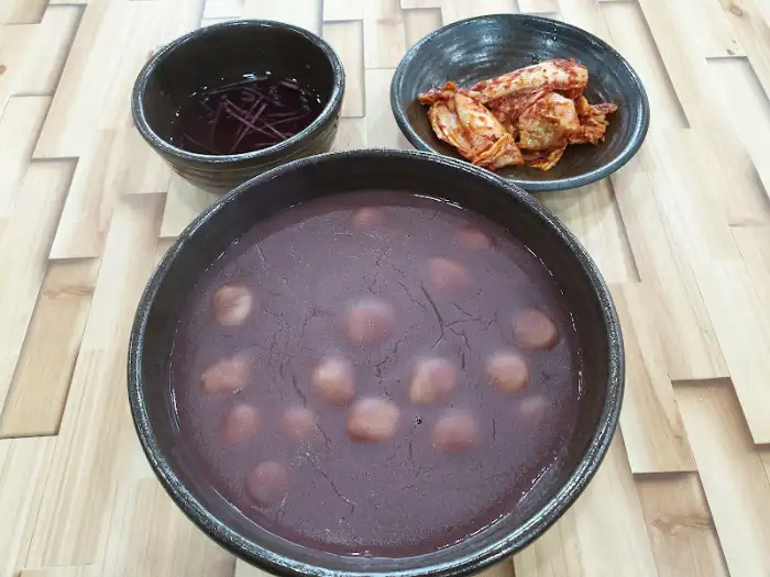 새알팥죽과 함께 나온 깍두기, 동치미 국물, 그리고 젓가락의 모습.