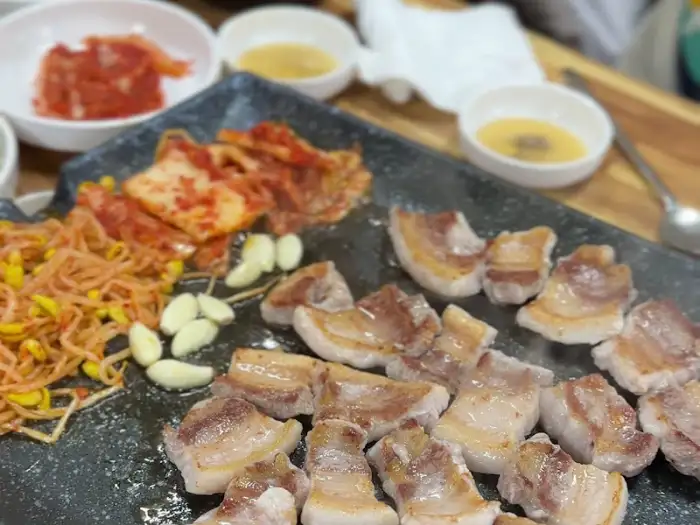 삼겹살과 곁들임 찬들이 차려진 불판 모습