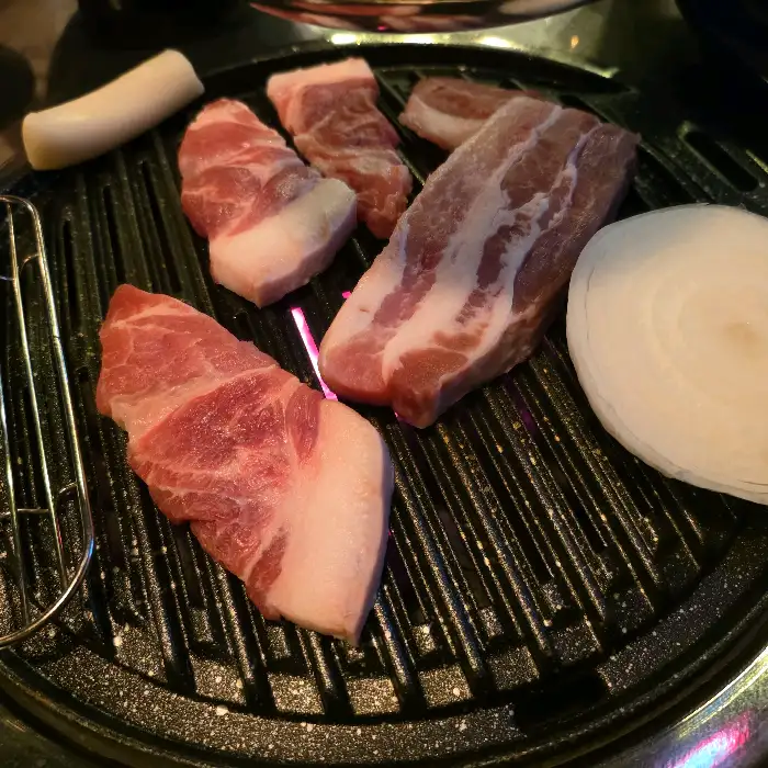 그릴 위에서 익어가는 두툼한 삼겹살과 목살