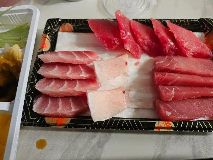 정갈하게 플레이팅된 참치회가 담긴 접시가 테이블 위에 놓여 있습니다.