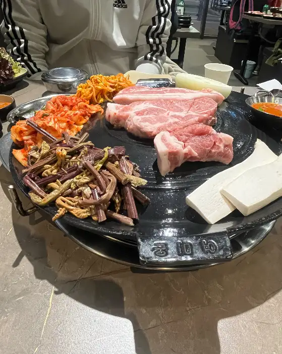 솥뚜껑 위에서 구워지고 있는 삼겹살과 채소