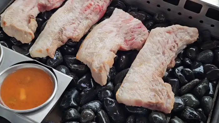 조약돌 위에서 지글지글 구워지는 흑돼지 오겹살