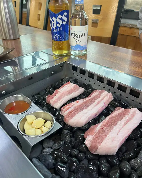 테이블에 놓인 흑돼지 구이와 술병