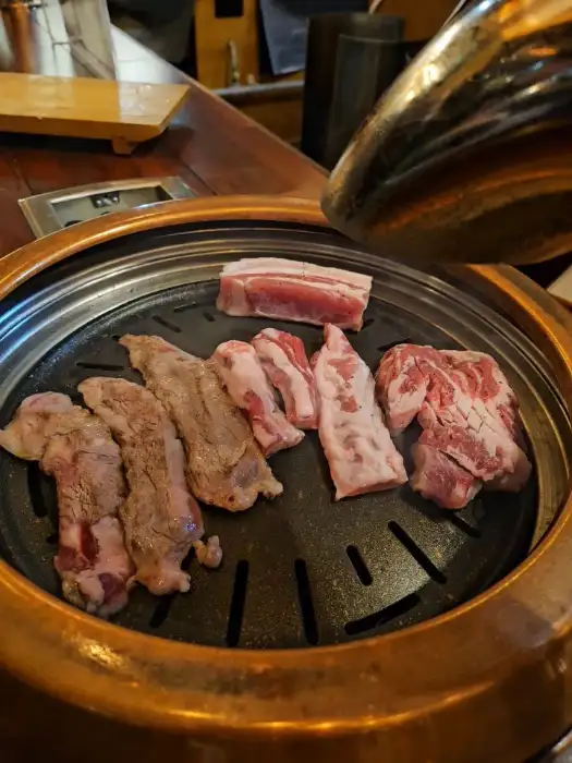기름이 잘잘 흐르는 생고기 부위들이 불판 위에 놓여 있는 모습