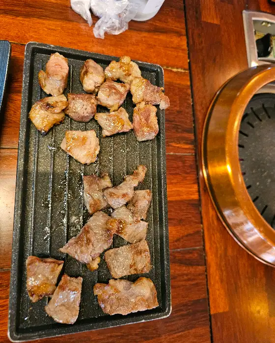 작은 화로 위에 따뜻하게 데워지고 있는 구워진 고기 조각들