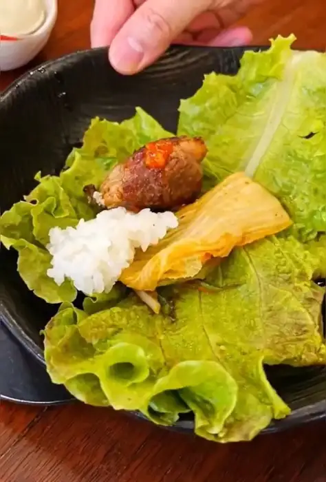 상추 위에 밥, 고기, 김치, 양념이 올라간 쌈의 모습