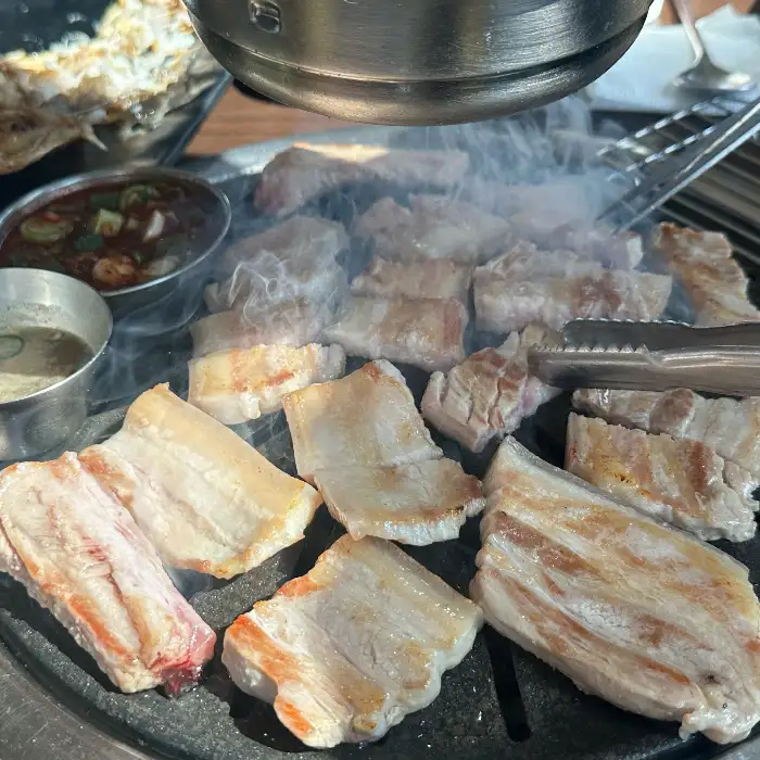 숯불 위에서 잘 익어가고 있는 흑돼지 조각들이 보입니다.