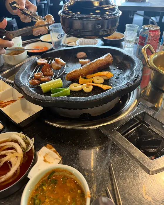 불판 위에서 맛있게 구워지고 있는 막창과 곁들임 채소들. 겉은 노릇하고 속은 촉촉한 막창의 모습이 군침을 돌게 합니다.