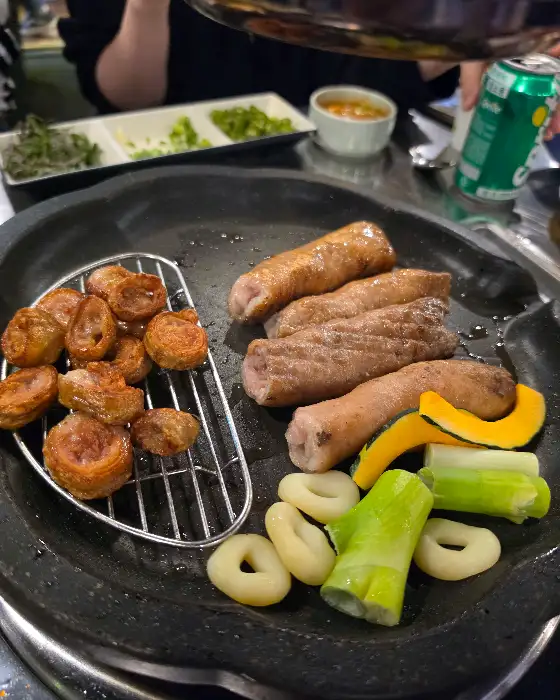 불판 위에서 막창과 채소가 함께 구워지고 있는 모습. 막창의 먹음직스러운 색감이 눈길을 끕니다.