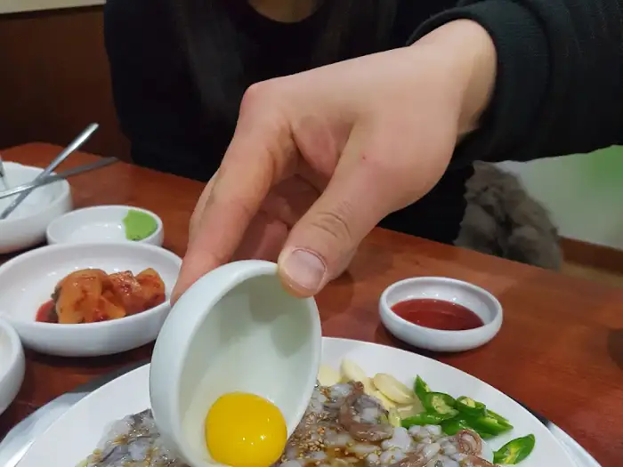 산낙지 육회에 계란 노른자를 올리는 모습