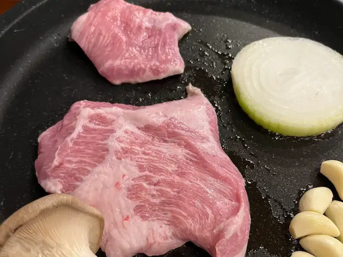 불판 위에 올라간 삼겹살과 버섯, 양파