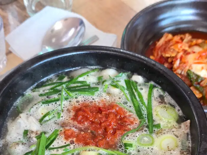 국밥 위로 붉은 양념과 파가 얹어진 모습이 먹음직스럽습니다. 국물의 뽀얀 색감과 조화롭게 어우러집니다.