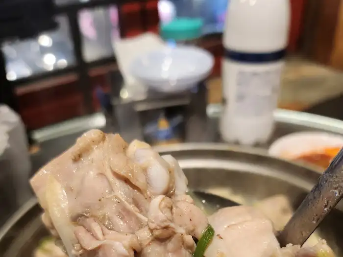 집게로 닭한마리 닭고기 조각을 들어 올리는 모습