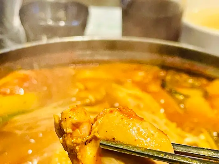집게로 닭볶음탕 양념이 잘 배인 닭고기를 집어 올리는 모습