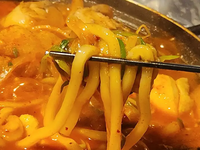 집게로 닭볶음탕에 들어있는 굵은 면을 들어 올리는 모습