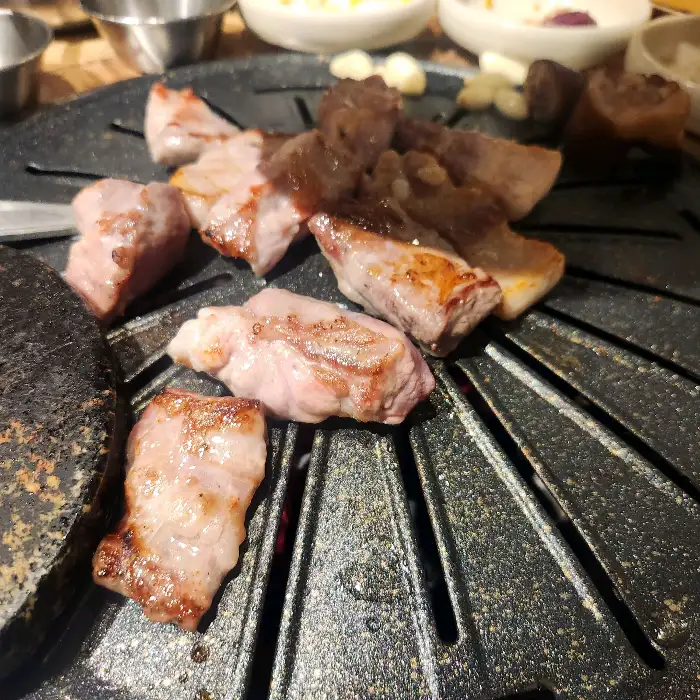 잘 익은 삼겹살 한 점이 불판 위에서 지글거리는 모습